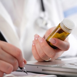 doctor holding pills writing prescription