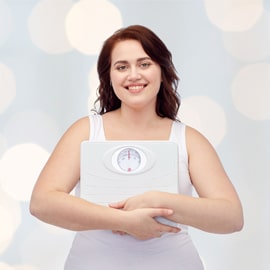 woman holding scale with smile on face